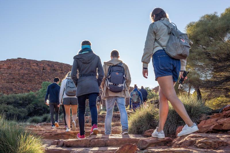 A  group of backpackers on a dirt path in the australian outback on a 5 day outback camping adventure