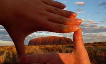 A pair of hands framing the view of Uluru in Australia on a 3 day UIluru Adventure