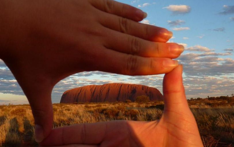 A pair of hands framing the view of Uluru in Australia on a 3 day UIluru Adventure
