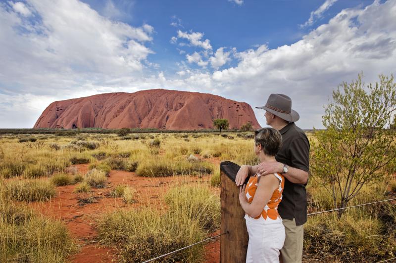 Two people looking at Uluru on a blue sky day on the 3 day Uluru Kata Tjuta & Kings Canyon Tour