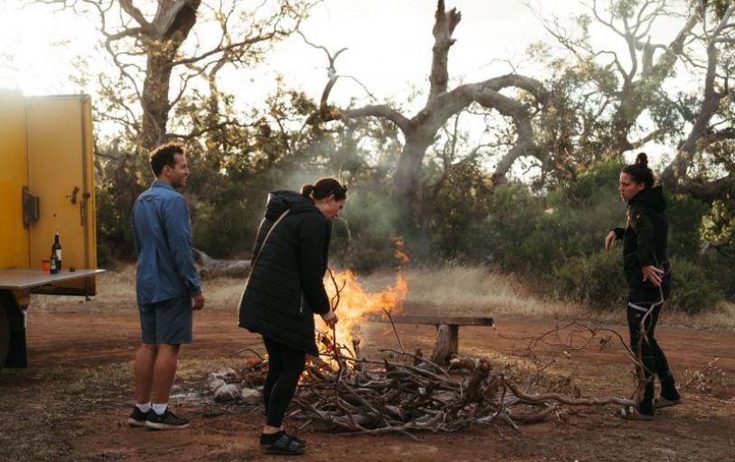 A girl with blonde hair in a black tshirt looking at sunset over an empty valley  in the Australian Outback on the 8 day Adelaide to Uluru adventure