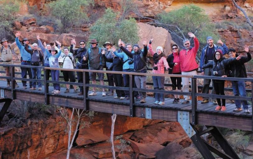 Six Backpackers hiking the red mountainous landscape of Uluru Kata Tjuta and Kings Canyon during the 3 night Rock the centre tour