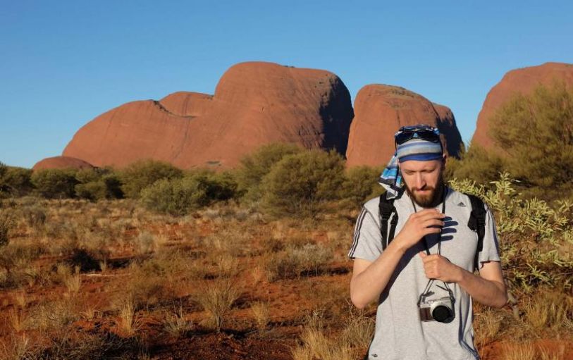 Six Backpackers hiking the red mountainous landscape of Uluru Kata Tjuta and Kings Canyon during the 3 night Rock the centre tour