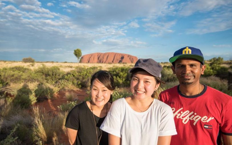 Six Backpackers hiking the red mountainous landscape of Uluru Kata Tjuta and Kings Canyon during the 3 night Rock the centre tour