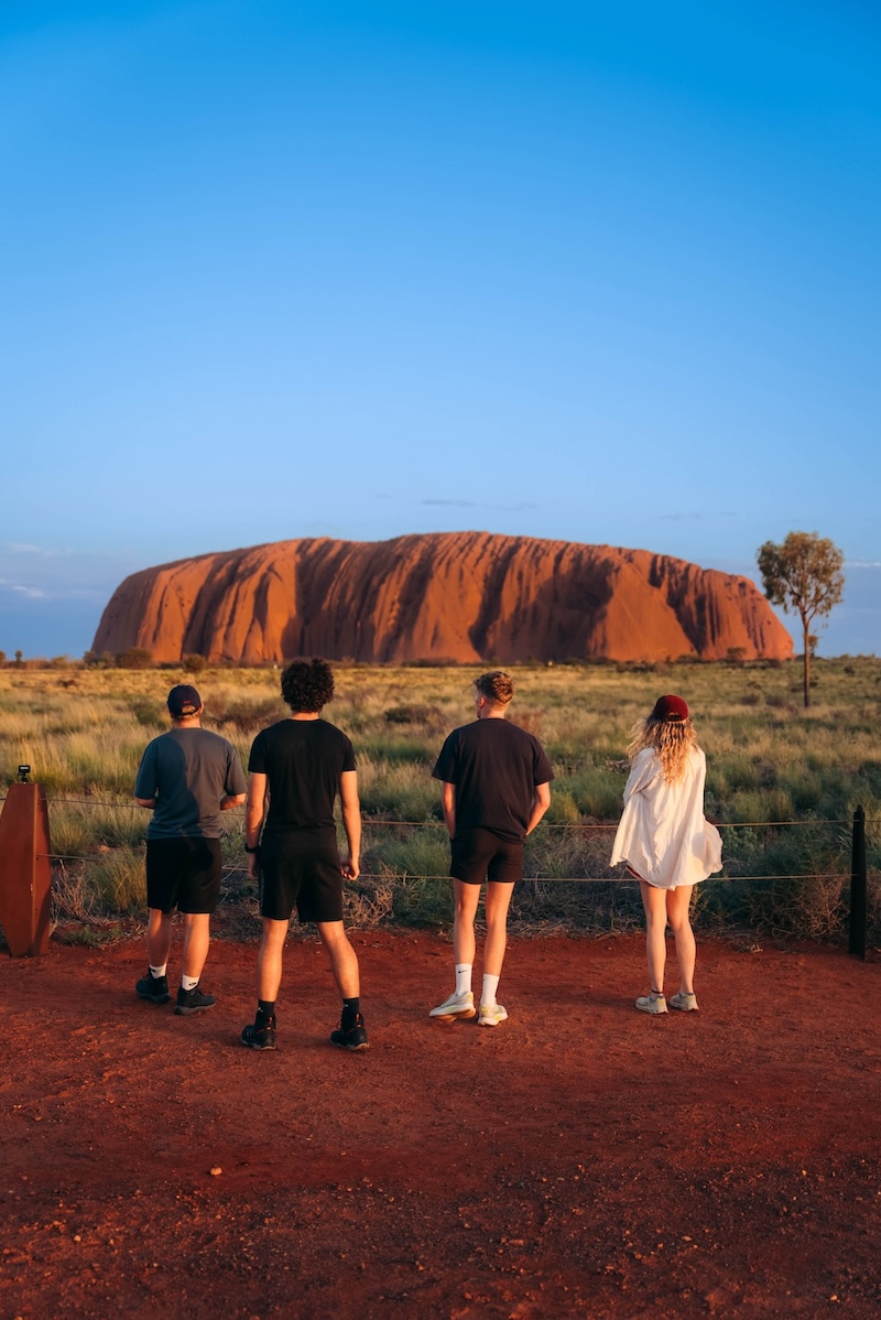 A group of backpackers in front of Uluru at sunset