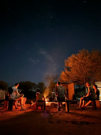Backpacker sitting in around a campfire on the 3 day uluru adventure