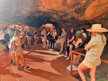 A group of backpackers learning about the history and culture of Uluru on a rock the centre tour