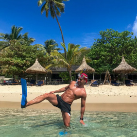 A man in flippers and snorkel standing in crystal clear sea water in Fiji booked by Peterpans