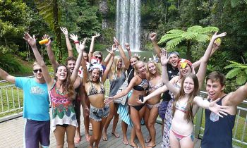 Group of friends wearing swimming costumes in front of the MilaMila waterfalls