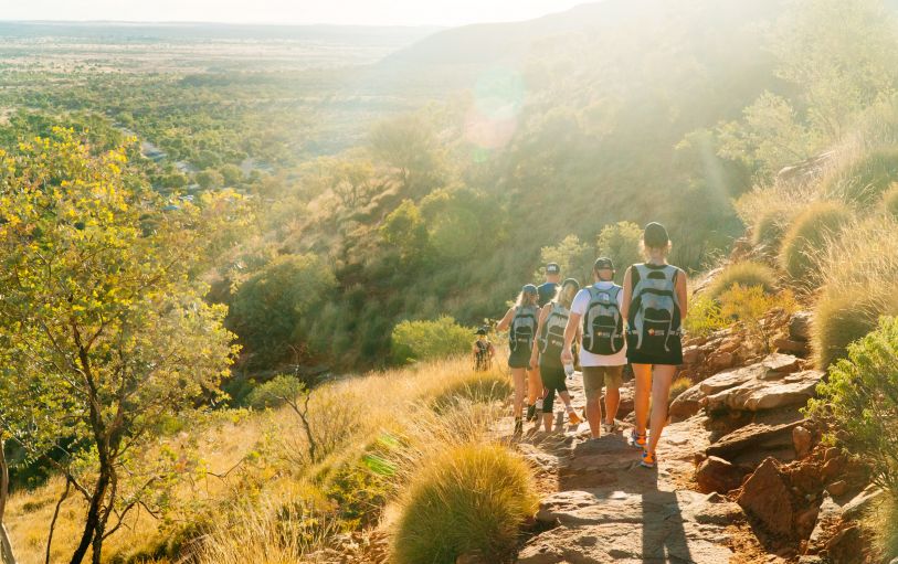 Three backpackers enjoying a glass of champagne at Uluru at sunset during the 3 Day Rock the Centre
