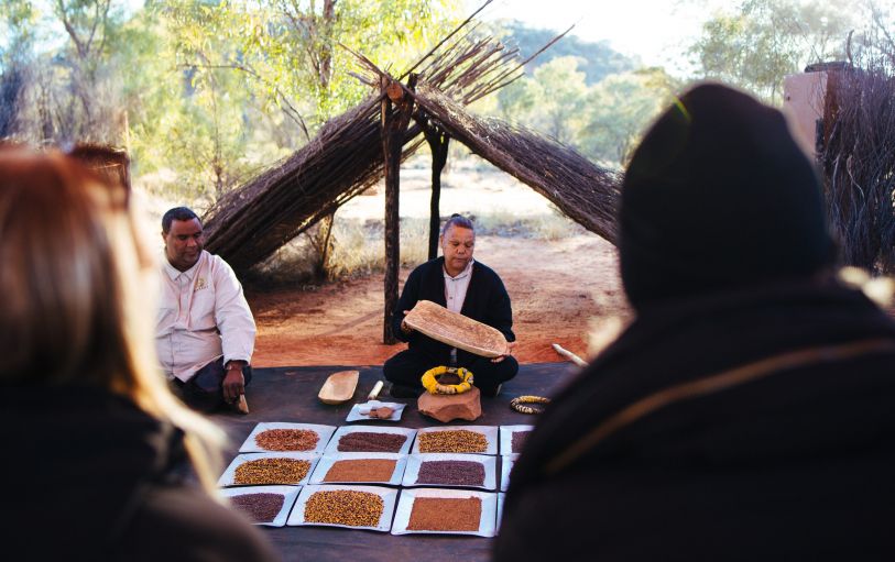 Three backpackers enjoying a glass of champagne at Uluru at sunset during the 3 Day Rock the Centre