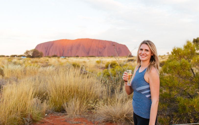 Three backpackers enjoying a glass of champagne at Uluru at sunset during the 3 Day Rock the Centre