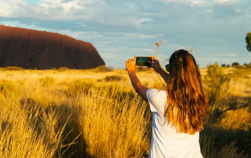 Three backpackers enjoying a glass of champagne at Uluru at sunset during the 3 Day Rock the Centre