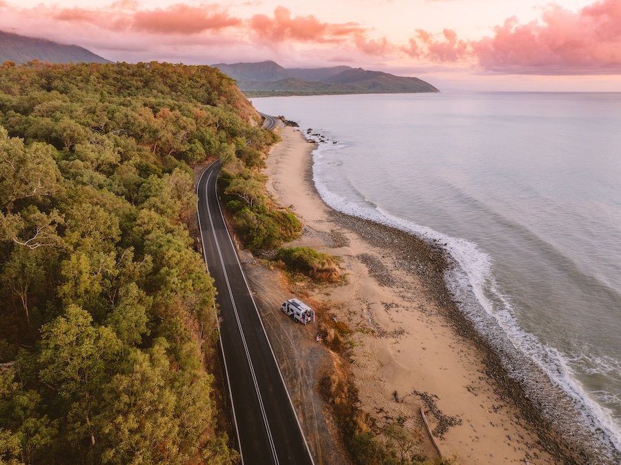 campervan beside the ocean in Cairns with the daintree rainforest behind it 