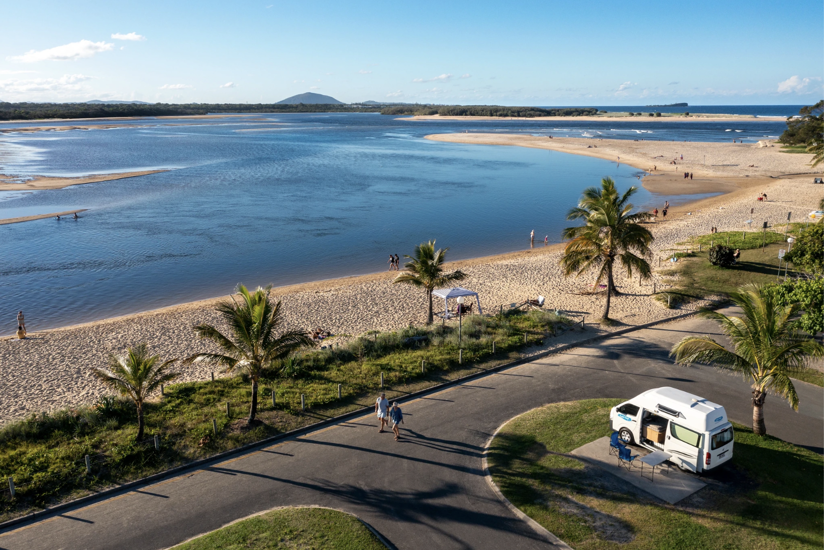 Backpackers in a van rented by Peterpans by the beach with palm trees