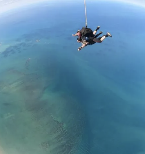 Two people freefalling over the Great Barrier Reef while doing a skydive in Cairns