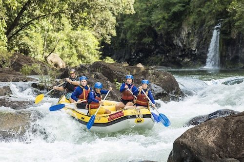 A group of backpackers having fun on a big yellow raft on Raging Thunder rafting trip on the Tully River